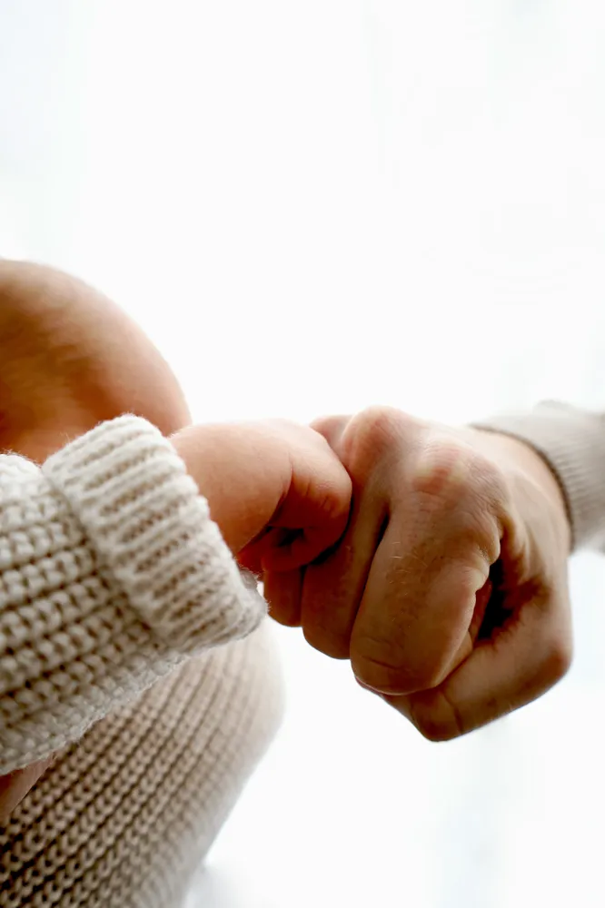 Detailaufnahme: kleine Babyhand neben der Faust des Vaters